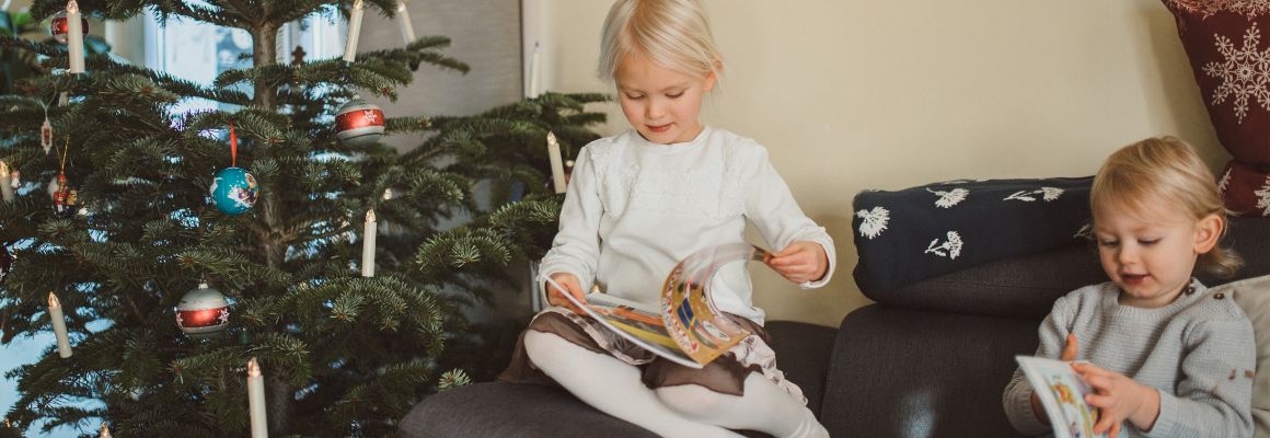 Kinder lesen Zeitschriften neben dem Weihnachtsbaum Kinder lesen Zeitschriften neben dem Weihnachtsbaum